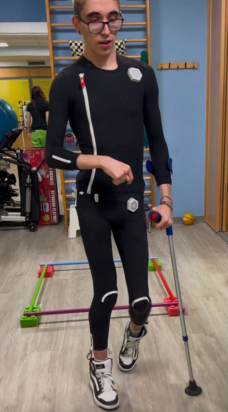 Un joven camina con bastón vistiendo el traje de neuromodulación Exopulse Mollii