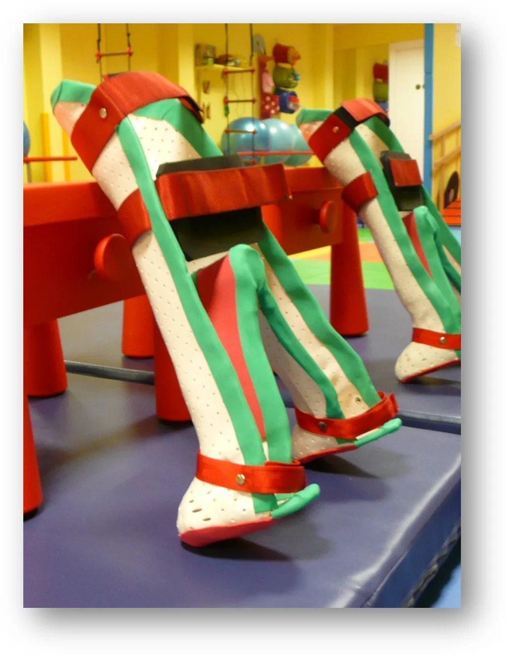 Two custom-made children's standers, decorated in green and red, in the therapy room