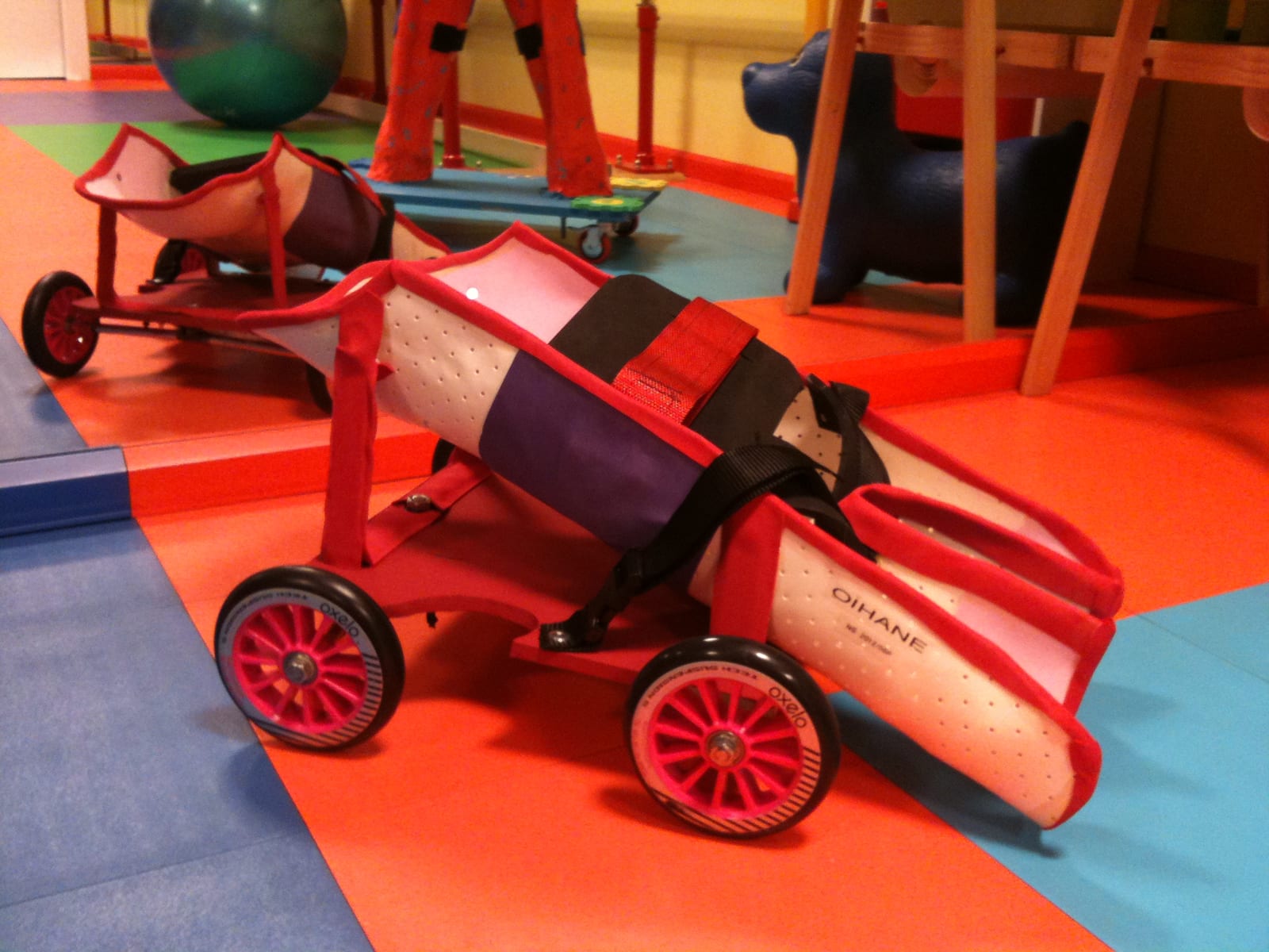 Two custom floor scooters with padded moulds and wheels in the clinic room