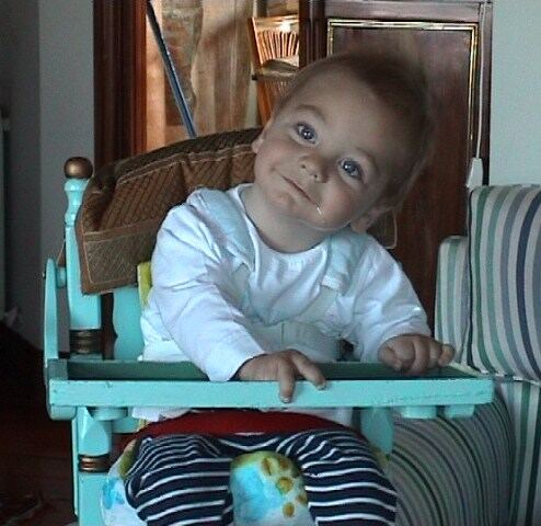 A baby sitting in a highchair with an adapted postural seat keeps the trunk upright and the hands free