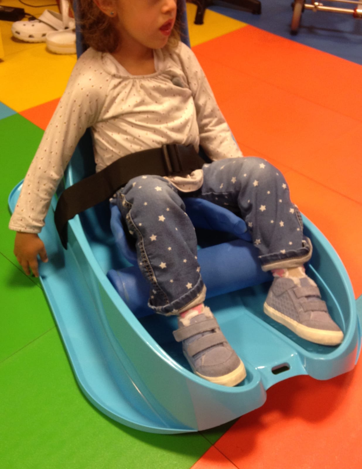 A girl sitting in an adapted floor seat keeps her trunk aligned