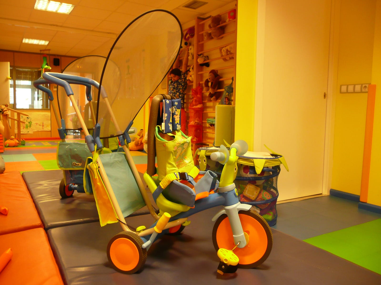 Adapted tricycle with backrest, harness and canopy in the play room