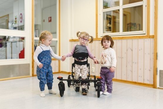 A girl walks in her NF-Walker holding hands with two friends